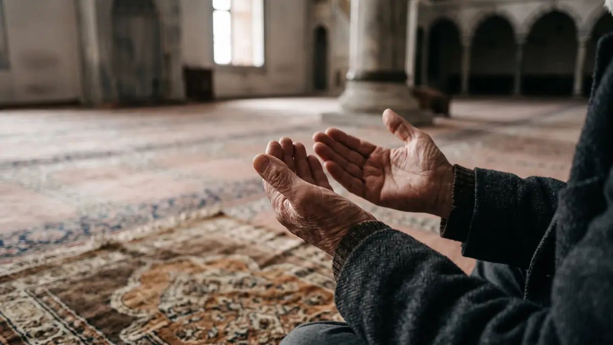 Cami köşesinde seccade üzerinde duaya açılmış eller
