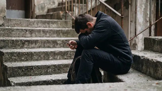 Merdivende elinde telefonla başını öne eğmiş pişman adam