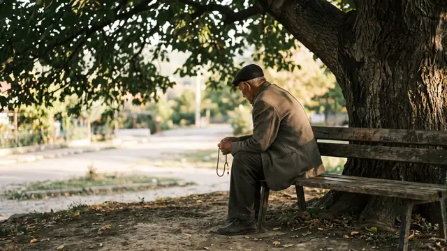 Ağaç altında bankta elinde tesbihle sabırla oturan yaşlı adam