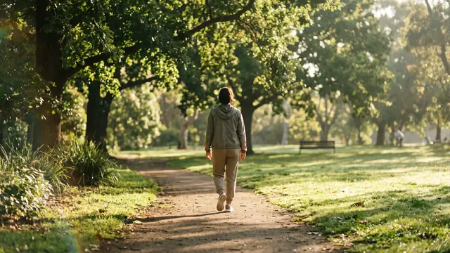 Sabah güneşinde yeşil parkta yürüyen kişi, arkadan
