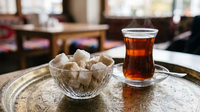 Tepside çay bardağı yanında cam kasede kesme şekerler